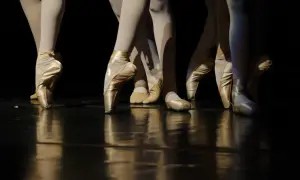 Nogi tancerek w baletkach tworzą piękny kontrapunkt na lśniącej scenie.