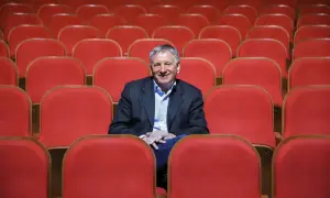 Uśmiechnięty dyrektor Teatru Osterwy siedzi wśród pustych, czerwonych foteli, gotów na kolejny spektakl.