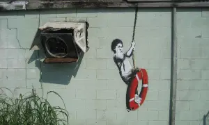 Dziecko na huśtawce z kołem ratunkowym, dzieło Banksy'ego. Kto to? Tajemniczy artysta uliczny.