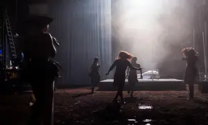 Scena teatralna z kobietami w ruchu, w tle łóżko. Może to być scena z życia Johna Proctora.