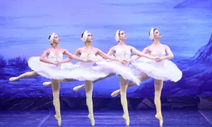 Cztery tancerki baletowe w białych tutu i opaskach na głowie, tworzące zsynchronizowany układ. Ich ruchy są precyzyjne, jakby wyśpiewywały muzykę **fortissimo**.