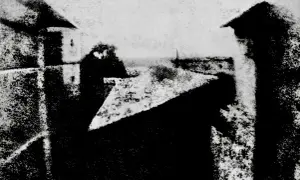Widok z okna, jeden z pierwszych fotografii. Dachy i budynki w szarościach.