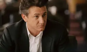Sean Penn w czarnym garniturze i białej koszuli, zamyślony. Jego role w filmach zapadają w pamięć.