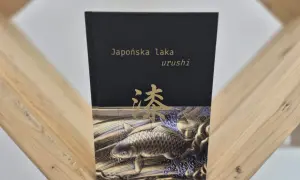 Okładka książki "Japońska laka urushi" z motywem złotej ryby koi i japońskiego znaku.