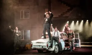 Król obsada na scenie, mężczyźni w strojach z epoki stoją na starym samochodzie, jeden z nich w mundurze.