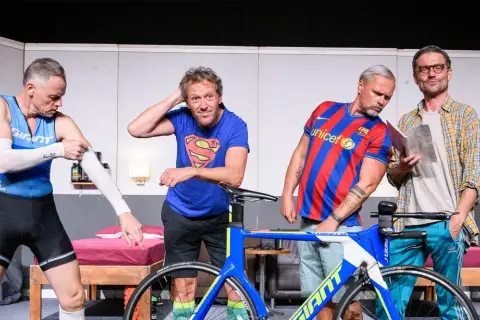 Triathlon story obsada: czterech mężczyzn w strojach sportowych i koszulkach, obok roweru.