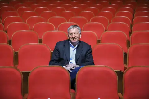 Uśmiechnięty dyrektor Teatru Osterwy siedzi wśród pustych, czerwonych foteli, gotów na kolejny spektakl.