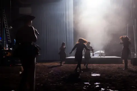 Scena teatralna z kobietami w ruchu, w tle łóżko. Może to być scena z życia Johna Proctora.