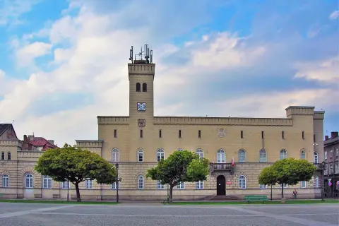 Budynek z wieżą i zegarem, otoczony drzewami. Czy to kordegarda? Co to za miejsce?