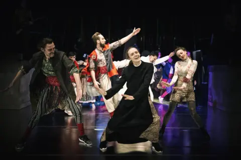 Aktorzy Narodowego Starego Teatru w Krakowie w barwnych strojach na scenie.