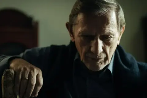Jan Englert w filmach, zamyślony, z dłonią na lasce.