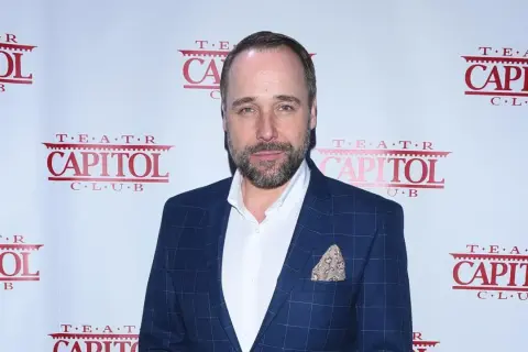 Łukasz Nowicki, znany z wielu filmów, pozuje na tle ścianki z logo Teatru Capitol.