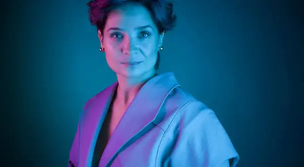 Barbara Sass, aktorka znana z filmów, w stylowej stylizacji, oświetlona neonowym światłem.