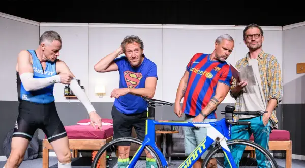 Triathlon story obsada: czterech mężczyzn w strojach sportowych i koszulkach, obok roweru.