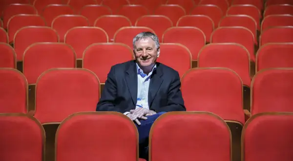 Uśmiechnięty dyrektor Teatru Osterwy siedzi wśród pustych, czerwonych foteli, gotów na kolejny spektakl.