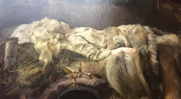 Młoda kobieta o blond włosach, Ellenai, śpi otulona futrem. Obok niej leży krzyż i książka.