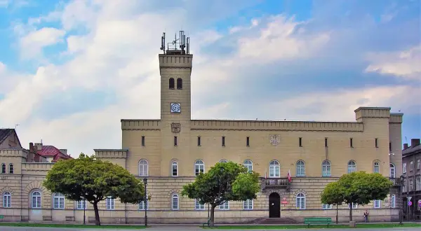 Budynek z wieżą i zegarem, otoczony drzewami. Czy to kordegarda? Co to za miejsce?