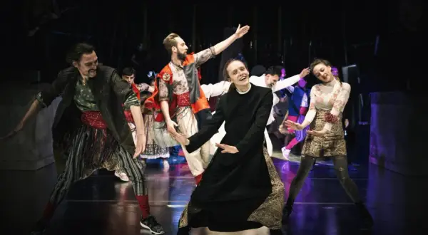 Aktorzy Narodowego Starego Teatru w Krakowie w barwnych strojach na scenie.