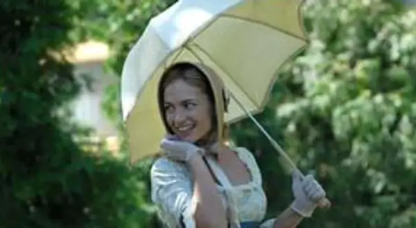 Uśmiechnięta młoda kobieta w białej sukience i rękawiczkach trzyma parasolkę. Scena z filmu "Śluby panieńskie" obsada.