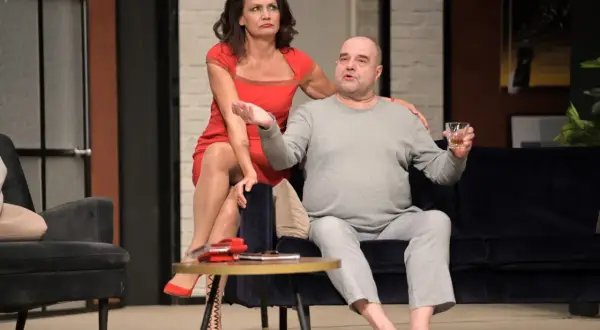 Kobieta w czerwonej sukience i mężczyzna w szarej piżamie, pijący whisky. Scena z przedstawienia "Kolacja dla głupca" obsada.