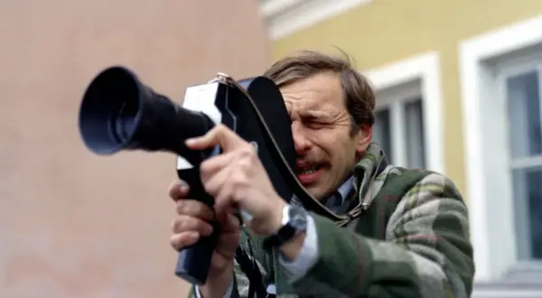 Jerzy Stuhr w filmie Kieślowskiego, z kamerą w ręku, skupiony na kadrze.