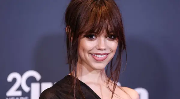 Jenna Ortega, aktorka znana z roli Wednesday Addams, uśmiecha się do obiektywu.