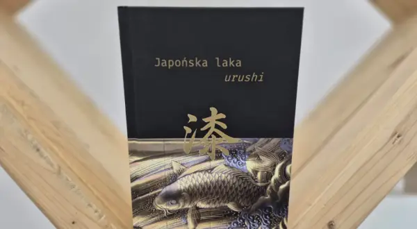 Okładka książki "Japońska laka urushi" z motywem złotej ryby koi i japońskiego znaku.