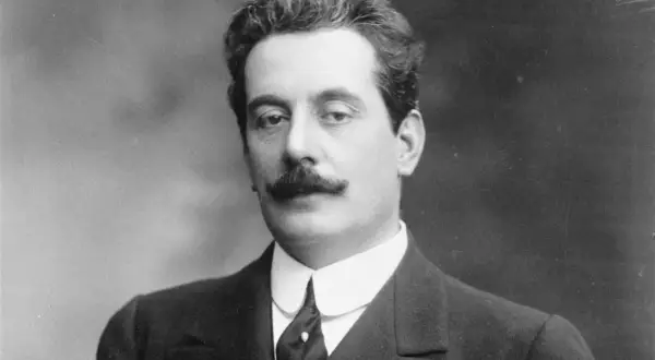 Giacomo Puccini, kompozytor słynnych oper, w eleganckim garniturze. Jego muzyka wciąż porusza serca słuchaczy.