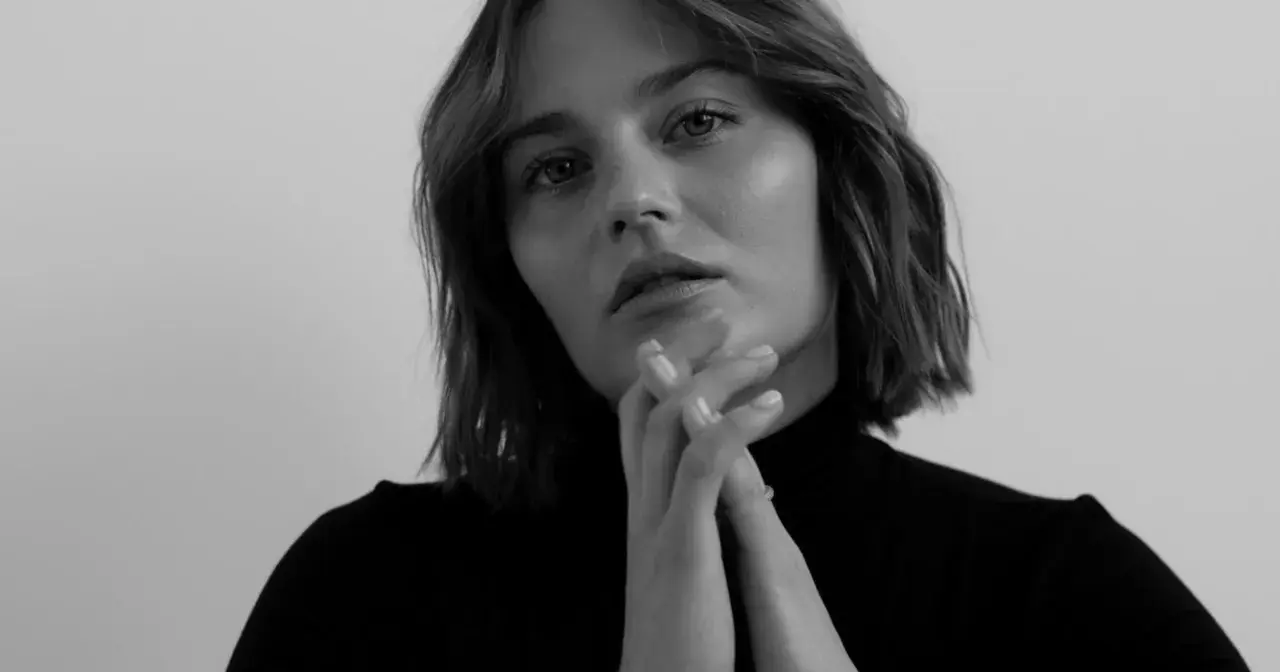 Katarzyna Sawczuk w czarnym golfie, z dłońmi złożonymi przed twarzą. Jej spojrzenie sugeruje głębokie przemyślenia, jakby przygotowywała się do roli w filmie.