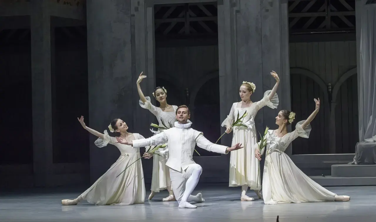 Tancerze w białych strojach, niczym z baletu "Romeo i Julia", tworzą na scenie romantyczną kompozycję.