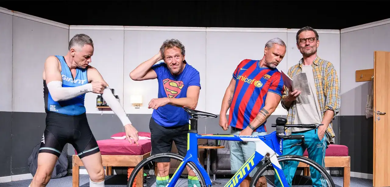 Triathlon story obsada: czterech mężczyzn w strojach sportowych i koszulkach, obok roweru.