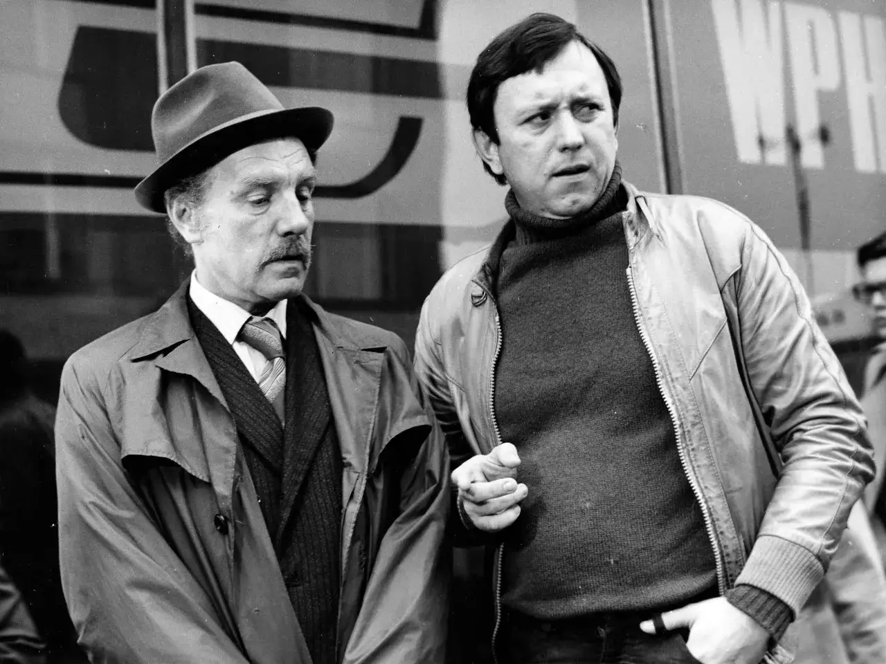 Dwóch mężczyzn, jeden w kapeluszu, drugi w kurtce, jakby dyskutowali. Scena z życia Zbigniewa Buczkowskiego, znanego z filmów, seriali i programów.