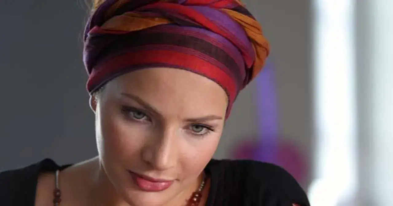 Anna Dereszowska w barwnym turbanie, jak z planu filmowego. Jej spojrzenie przyciąga uwagę.