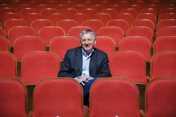 Uśmiechnięty dyrektor Teatru Osterwy siedzi wśród pustych, czerwonych foteli, gotów na kolejny spektakl.