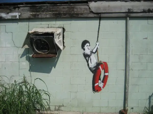 Dziecko na huśtawce z kołem ratunkowym, dzieło Banksy'ego. Kto to? Tajemniczy artysta uliczny.