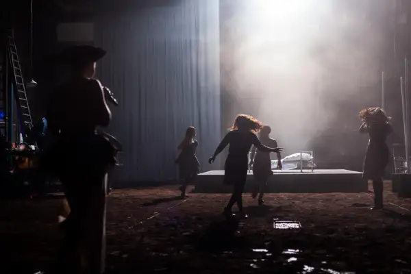 Scena teatralna z kobietami w ruchu, w tle łóżko. Może to być scena z życia Johna Proctora.