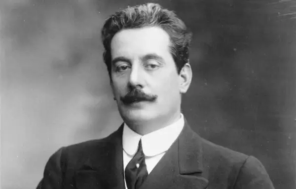 Giacomo Puccini, kompozytor słynnych oper, w eleganckim garniturze. Jego muzyka wciąż porusza serca słuchaczy.